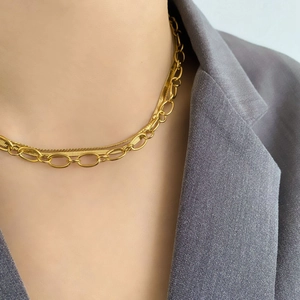 Detail of layered gold necklaces featuring a snake chain and oval link chain on a model