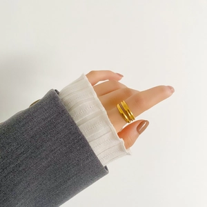 Dettaglio di un anello a doppio strato minimalista dorato sull'indice con finitura lucida