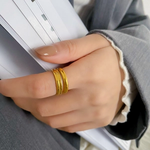 Dettaglio di anelli sovrapponibili dorati minimalisti indossati su abito formale