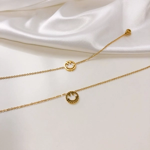 Gros plan de colliers à pendentif smiley doré sur fond de soie blanche