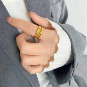 Anello incrociato a doppio strato minimalista in oro indossato da una modella in abito formale