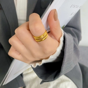 Dettaglio dell'anello a tre strati in oro indossato su uno sfondo ufficio sobrio