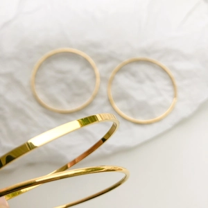 Macro shot of minimalist gold plated titanium steel bracelets on textured white paper