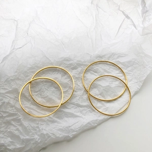 Set of four polished gold minimalist bangles on a textured white background
