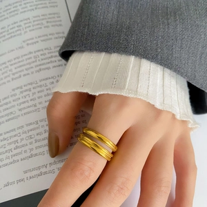 Dettaglio di un set di anelli dorati minimalisti indossati con un outfit da ufficio