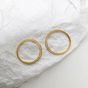 Detail shot of minimalist gold plated bangle pair on textured white background