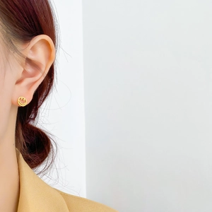 Gros plan sur une boucle d'oreille dorée minimaliste en forme de smiley évidé