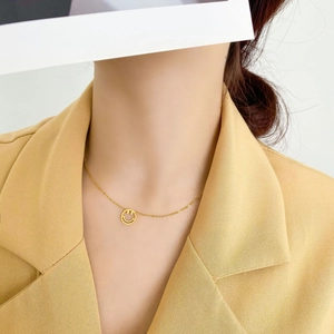 Vue détaillée d'un collier doré avec pendentif smiley porté avec un blazer beige chic