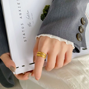 Anello a triplo strato incrociato in oro minimalista indossato a mano in stile urbano