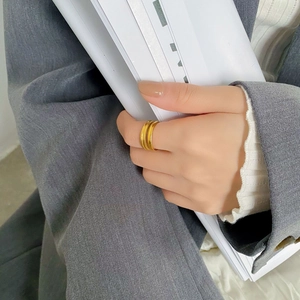 Dettaglio di un anello multistrato dorato minimalista indossato con un blazer