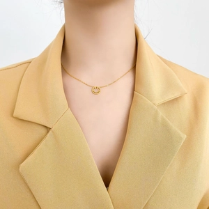 Gros plan d'un délicat collier avec pendentif smiley doré porté sur le cou