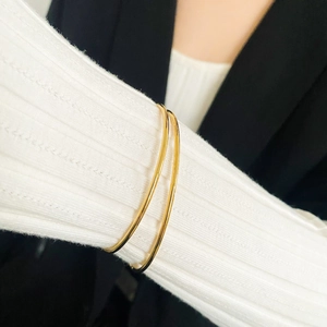 Close-up of minimalist gold plated stainless steel bangles on a woman's wrist