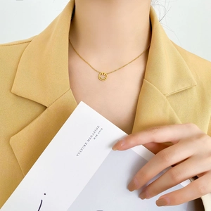 Gros plan d'un collier avec pendentif visage souriant doré porté par un mannequin