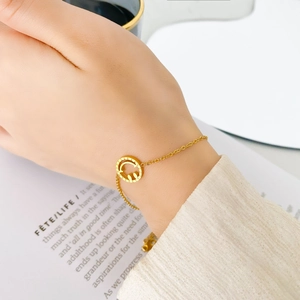Bracelet chaîne dorée délicat avec pendentif smiley évidé au poignet d'une femme