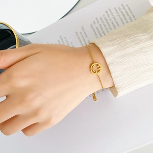 Détail d'un bracelet en chaîne dorée minimaliste avec pendentif smiley au poignet