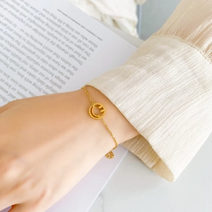 Gros plan du bracelet doré avec pendentif smiley et chiffres romains sur mannequin
