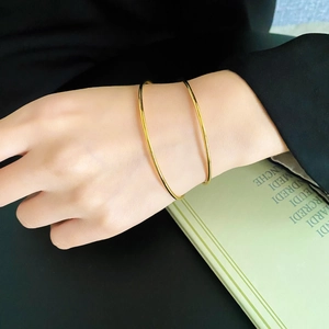 Polished minimalist gold-plated titanium steel bangles set worn on a female wrist