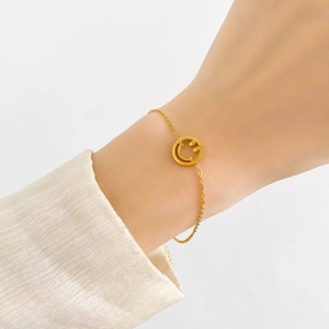 Détail d'un bracelet doré minimaliste avec pendentif smiley au poignet d'une femme