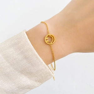 Détail d'un bracelet doré avec pendentif smiley ajouré et chaîne ajustable délicate
