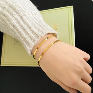Close-up of dual minimalist gold-plated titanium steel bangles with a polished finish