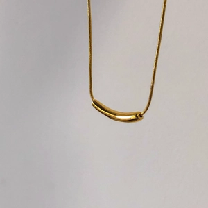 Minimalist gold snake chain necklace featuring a polished curved bar pendant for women
