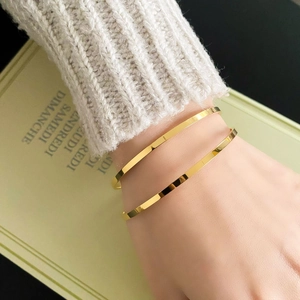 Polished gold-plated stainless steel bangles styled with knitwear and a book background