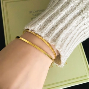 Detail showing smooth gold-plated bangle and hammered texture cuff bracelet set