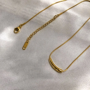 Detailed close-up of K18 gold minimalist snake chain necklace with curved bar pendant