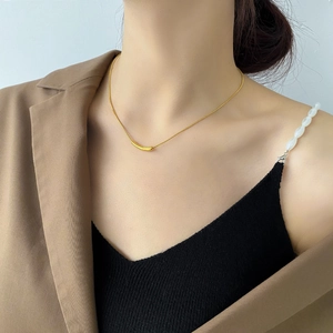 Minimalist gold snake chain necklace with curved tube pendant worn by a female model
