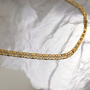 Détail macro d'un collier plaqué or avec des maillons rectangulaires creux uniques