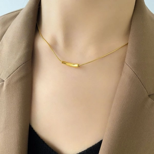 Close-up of minimalist gold snake chain necklace with curved bar pendant on a model