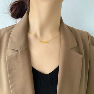 Detail of minimalist 18K gold plated tube pendant on slim snake chain necklace