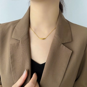 Close-up of minimalist gold curved bar necklace on neck with snake chain style