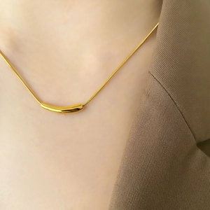 Close-up of minimalist gold snake chain necklace with curved bar pendant on a model