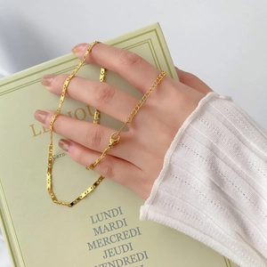 Collier chaîne dorée à maillons nez de cochon avec fermoir mousqueton sur fond de livre