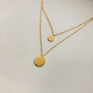 Detail of layered gold double strand necklace featuring minimalist circular pendants