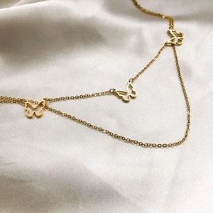 Elegant gold butterfly layered necklace featuring hollow charms on a cross chain