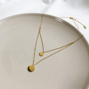 Close-up of double-layer gold necklace with two round pendants and K18 hallmark detail