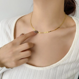 Gros plan d'un collier à maillons nez de cochon doré porté sur une maille blanche