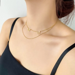 Close-up of double-layered gold butterfly necklace worn by a model on a black top