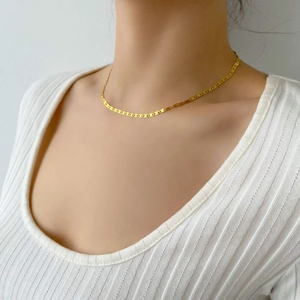 Détail d'un collier chaîne maille marine dorée délicate porté par un mannequin femme