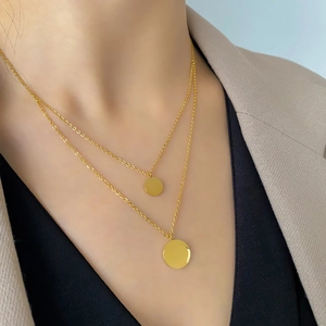 Close-up of double-layered gold necklace with two polished round pendant discs