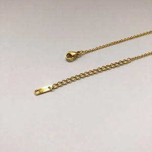 Détail du fermoir mousqueton et de la chaîne d'extension réglable du collier doré