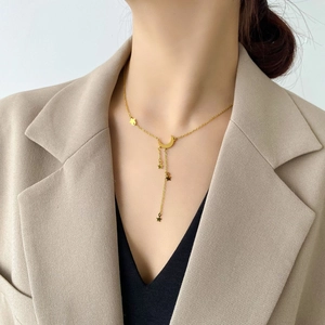 Élégant collier à pampilles lune et étoile dorées porté par un mannequin en costume