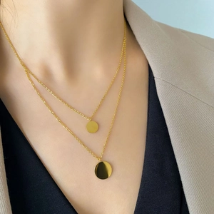 Close-up of double-layered gold necklace with round pendants on a female model