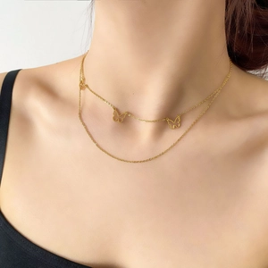 Close-up of double-layer gold chain necklace with delicate butterfly pendants on neck