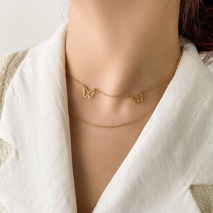 Detail of elegant double-layered gold butterfly necklace on female model neck