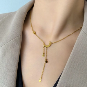 Détail du collier à pampilles lune et étoile dorées porté pour un look élégant