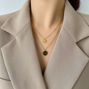 Close-up of double-layer gold necklace with circular pendants on a female model