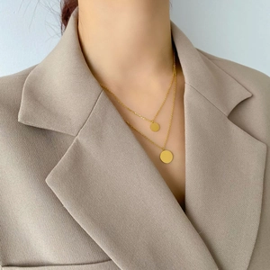 Close-up of minimalist layered gold necklaces with two round pendants on professional blazer